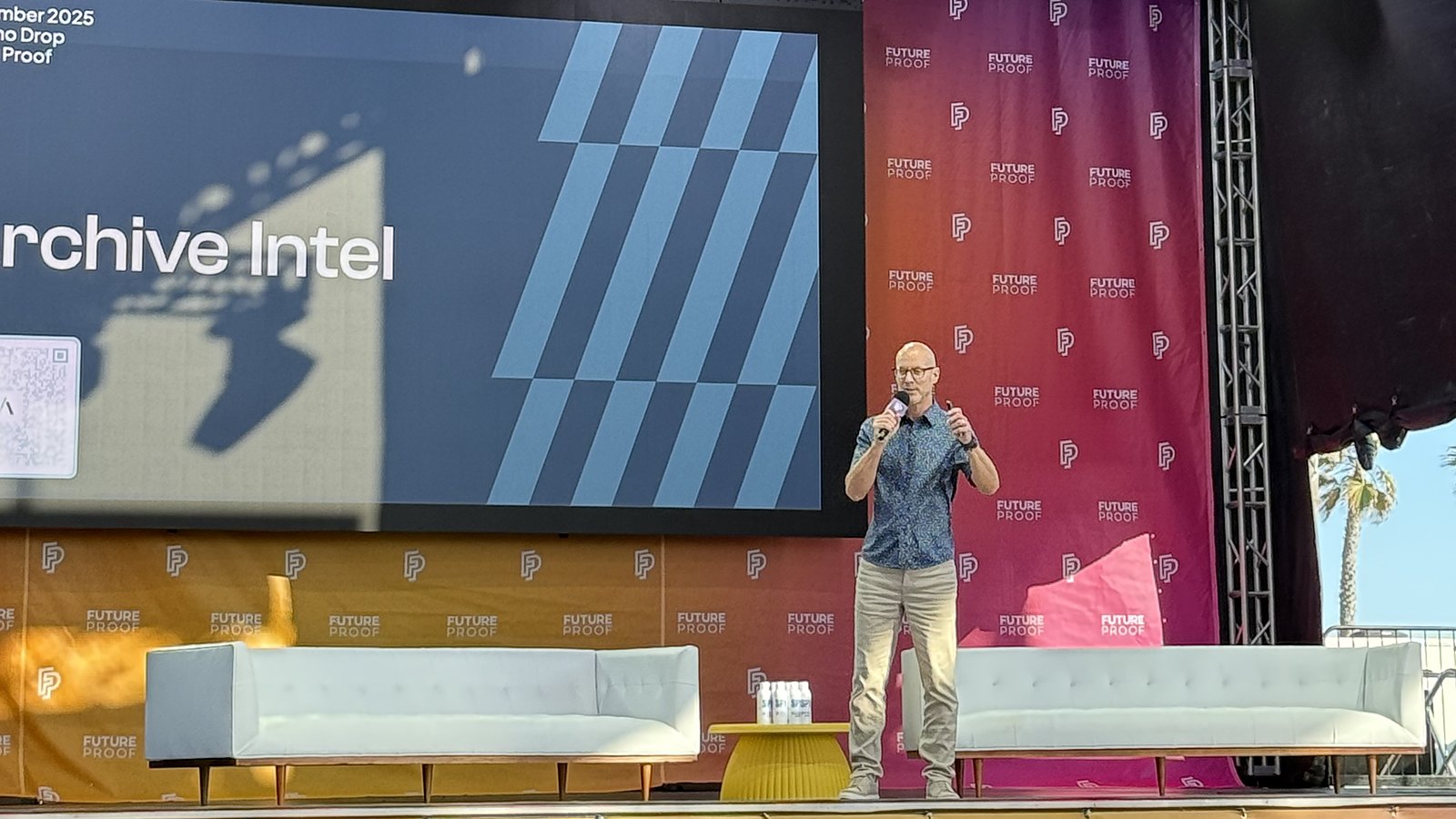 Larry Shumbres on the Future Proof Festival Ocean Stage, microphone in hand, with the Archive Intel AI Demo Drop title slide behind him